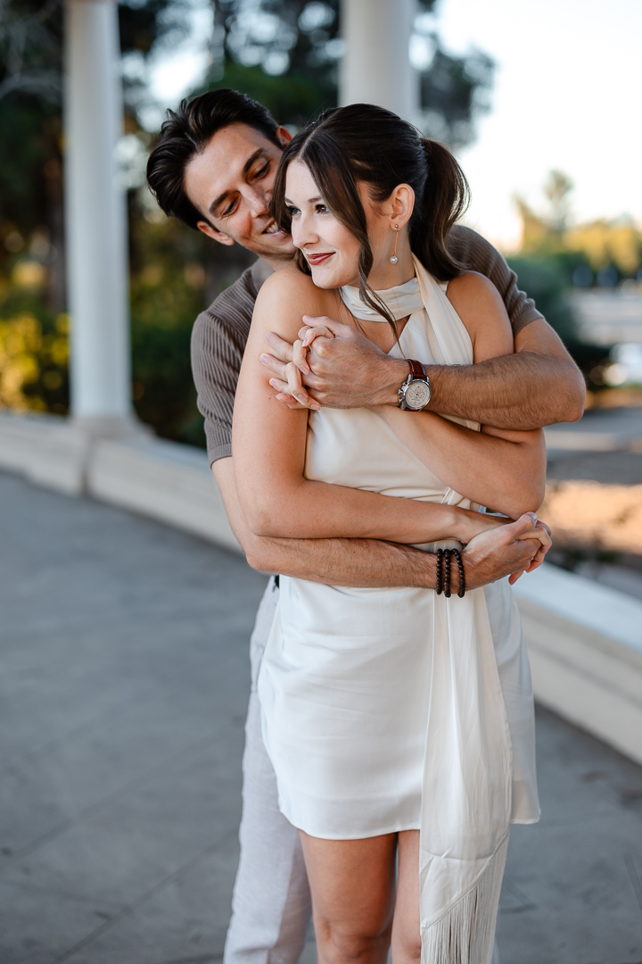 Captured by Poppy & Hive Photography, San Diego Balboa Park Engagement Session: Sam & Ian | Category: Engagements | Keywords: Happiness, Shoulder, Formal wear, Smile, Fashion, Standing, Collar, Dress, Waist, Dress shirt, Photograph, White, Monochrome photography, Black, Monochrome, Black and white, Grey, Human back, Interaction, Love, Romance, Event, Neck, Black hair, People in nature, Arch, Facial expression, Gesture, Column, Leisure, Honeymoon, Bride, Summer, Vacation, Brown hair